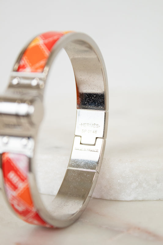Silver bracelet with red and white pattern on a light background