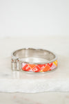 Silver bracelet with a colorful band on a white marble surface