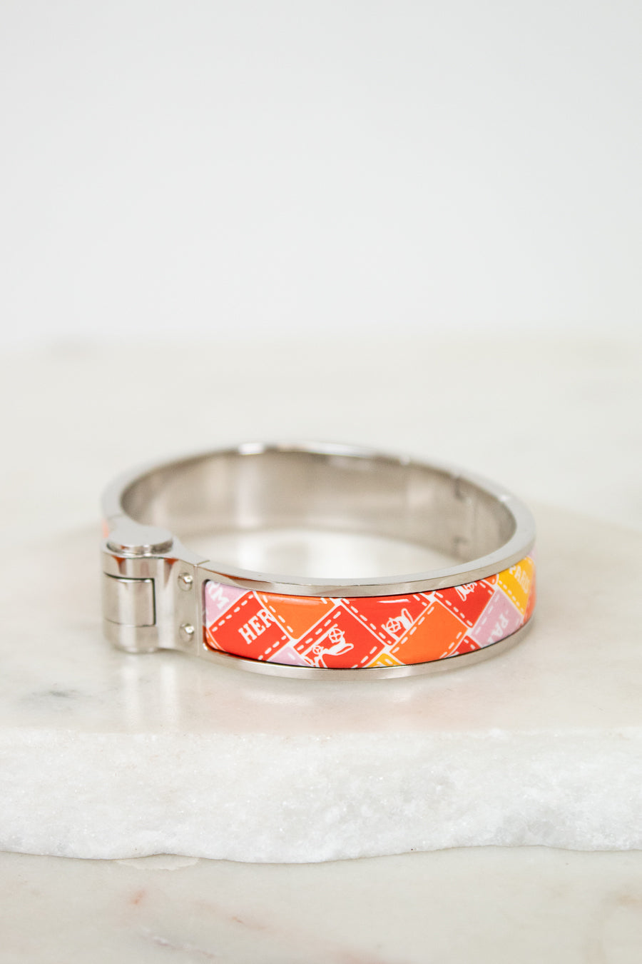 Silver bracelet with a colorful band on a white marble surface