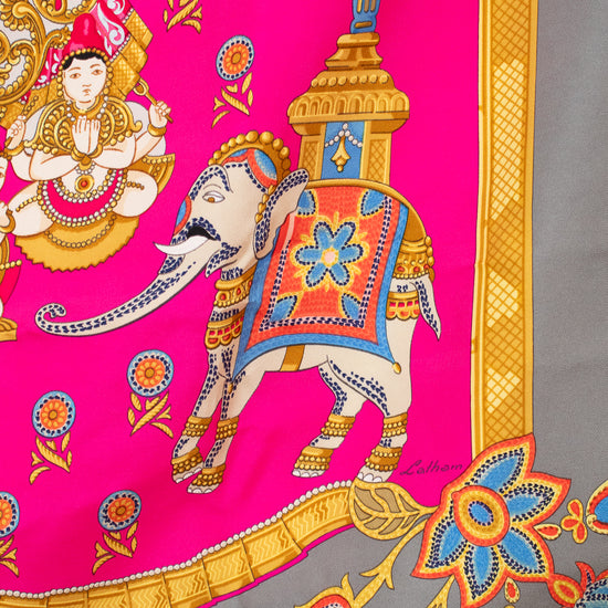 Colorful scarf with elephant design and Hermès Paris logo on a pink and gray background