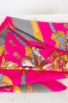 Colorful patterned fabric scarf with pink and gold design on a white background