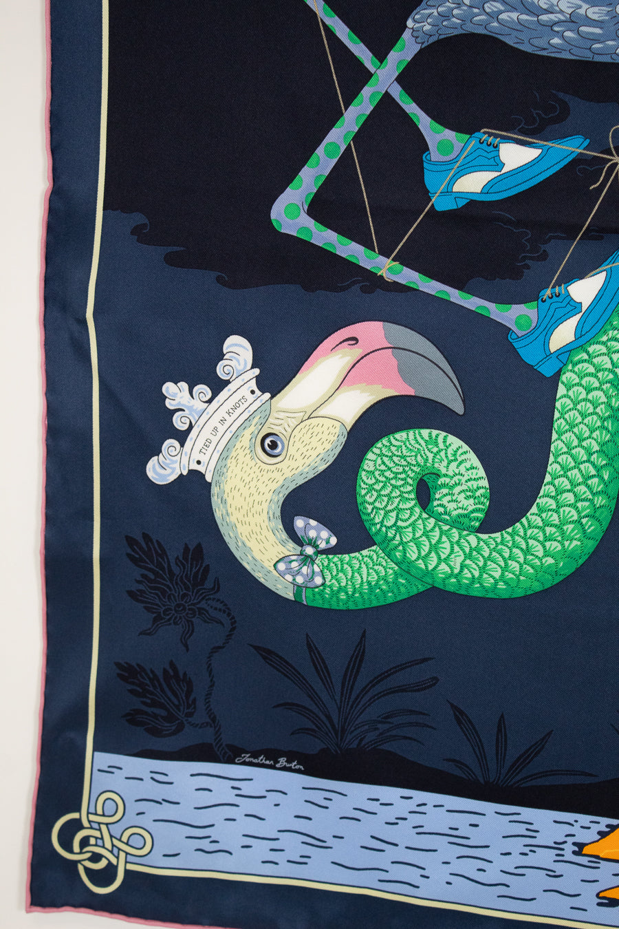 Silk scarf with a colorful bird design on a dark blue background