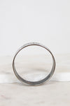 A silver-toned metal bangle bracelet with a textured, enamel and pattern on the outer surface, displayed on a white marble surface against a white background.