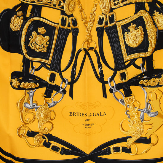 Decorative scarf with horse bridle with gold and black details on a yellow background, featuring 'Brides de Gala' branding.
