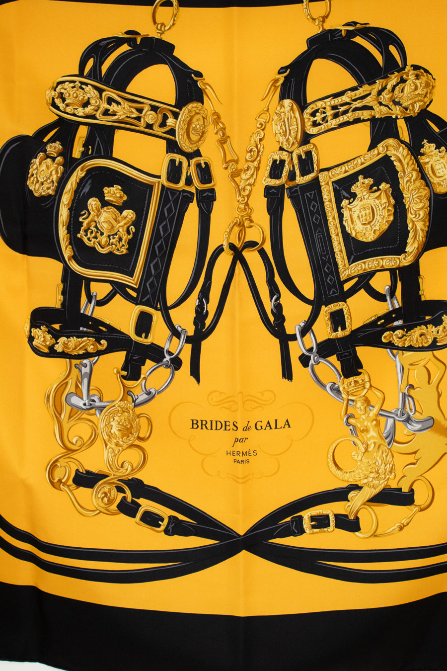 Decorative scarf with horse bridle with gold and black details on a yellow background, featuring 'Brides de Gala' branding.