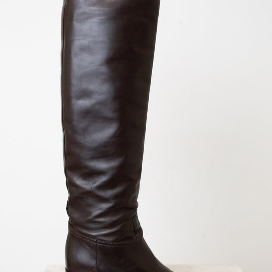 A side view of the HERMES black boot, showing the black heel and slouchy wrinkle. With a white background.