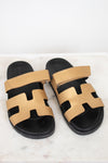 Pair of gold and black sandals on a white marble surface