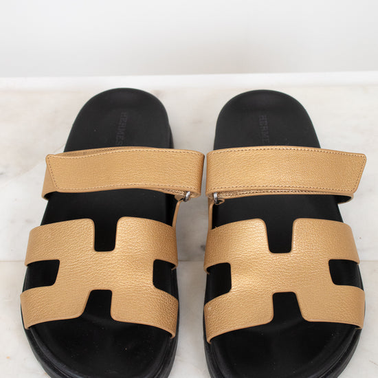 Pair of black and gold sandals on a white background