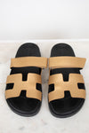 Pair of black and gold sandals on a white background