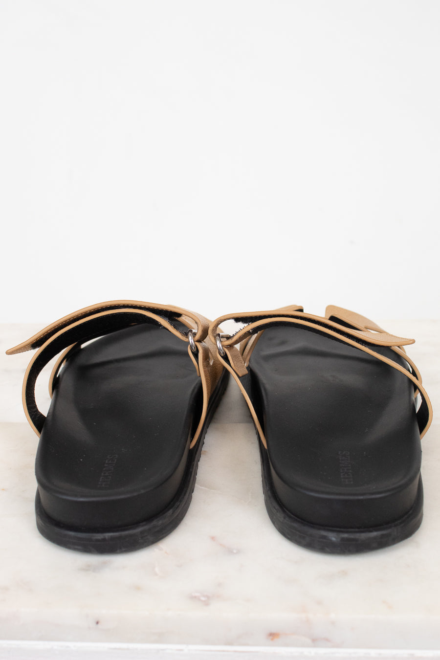 Heel of black and gold sandal on marble surface