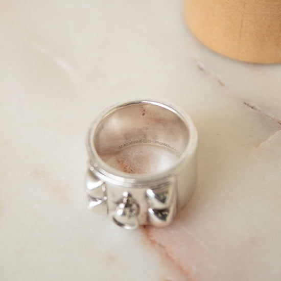 I aerial view of the silver HERMES ring showing the 3D aspect of the shapes. Shown on a marble plate with red streak.