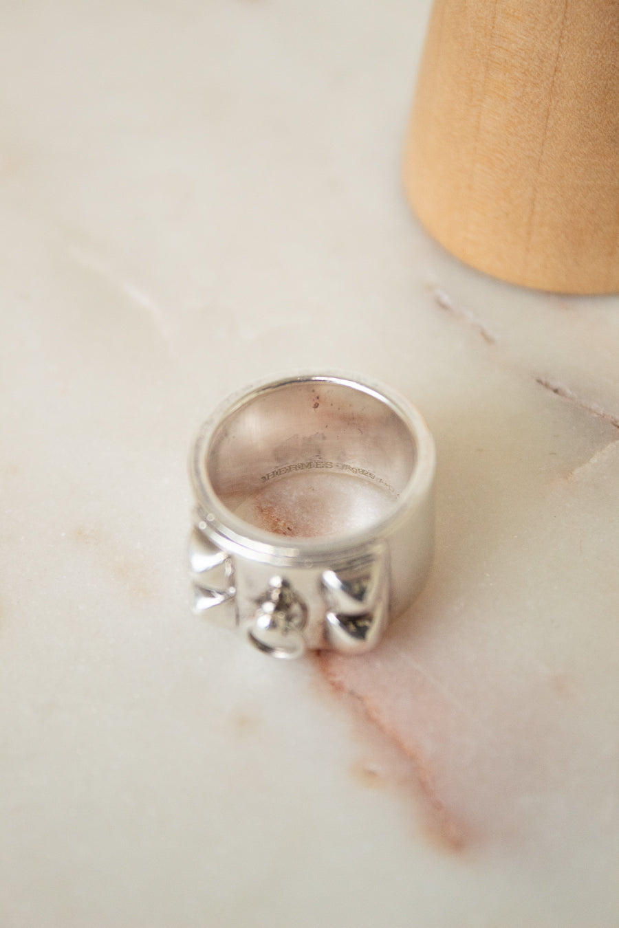 I aerial view of the silver HERMES ring showing the 3D aspect of the shapes. Shown on a marble plate with red streak.