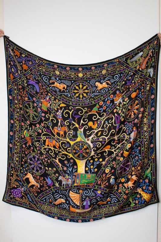  a black silk scarf with a vibrant, multicolored bohemian print featuring peacocks, flowers, and traditional patterns against a white background