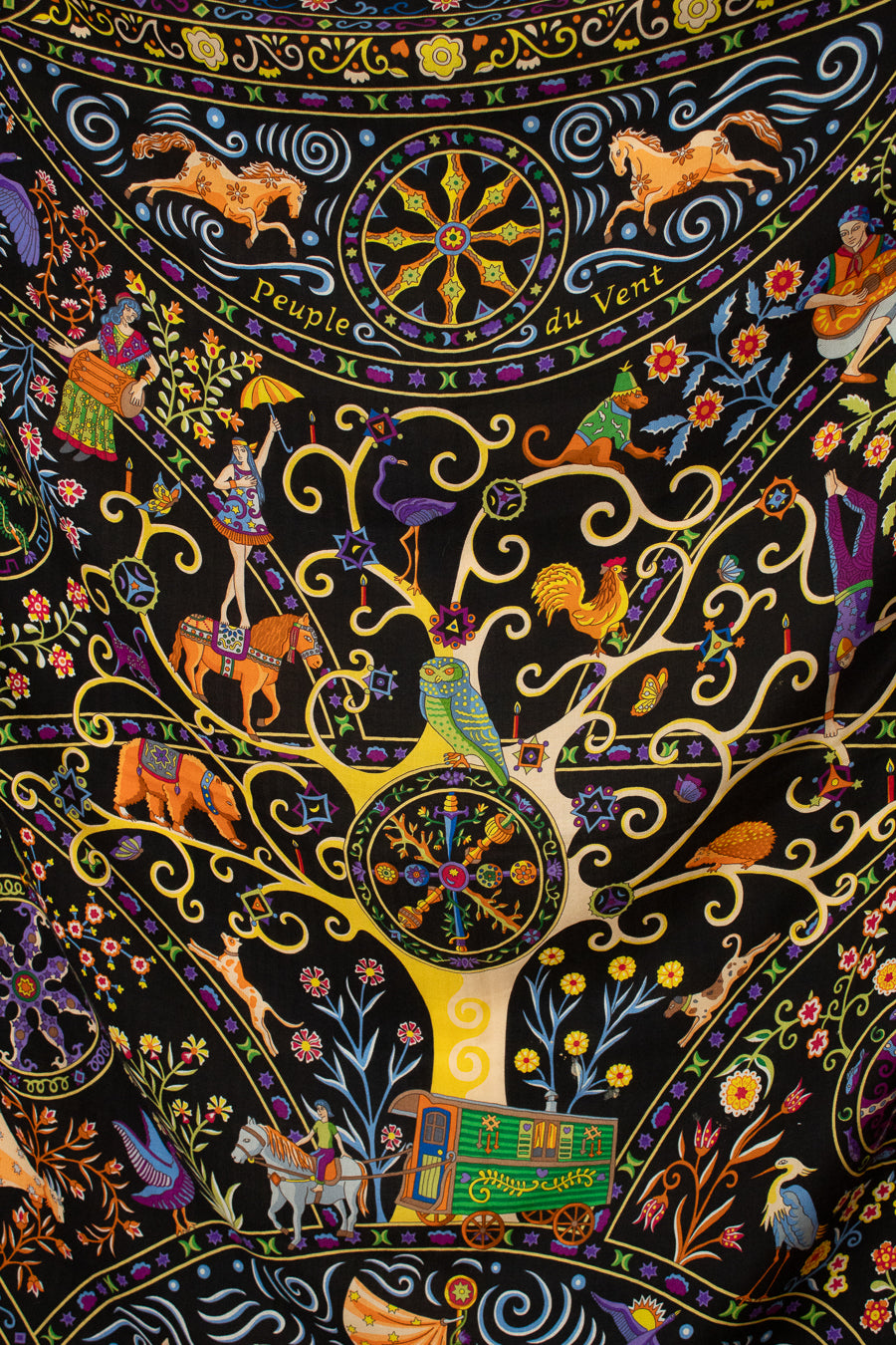A close-up of a highly detailed, colorful Indian folk art textile scarf featuring a central tree motif with birds, horses, and decorative elements on a black background.