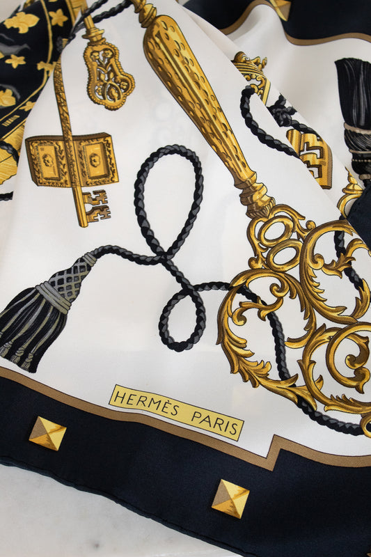 Hermès Paris scarf with gold and black design on a white background