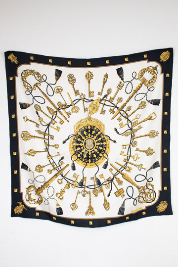 Decorative scarf with gold and black key pattern on a white background