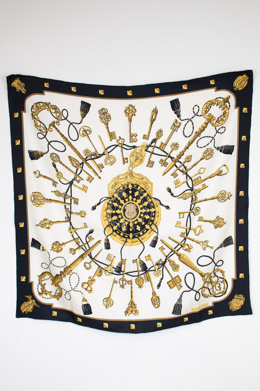 Decorative scarf with gold and black key pattern on a white background