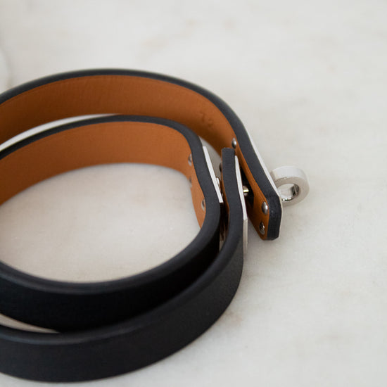 Two leather belts, one black and one brown, on a marble surface.