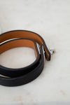 Two leather belts, one black and one brown, on a marble surface.