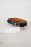 Black leather belt with silver buckle on a white surface