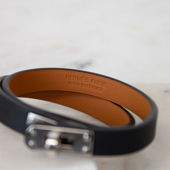 Black leather bracelet with a silver clasp on a light gray background