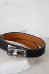 Black leather bracelet with a silver clasp on a light gray background