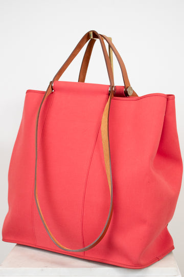 Large red canvas tote bag with brown leather straps on white background