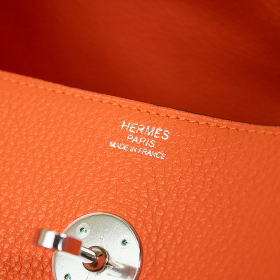Close-up of an orange textured leather bag interior with silver-tone hardware and visible HERMES PARIS MADE IN FRANCE branding stitched into the leather.
