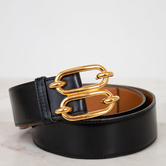 Black belt with a gold chain buckle on a light background