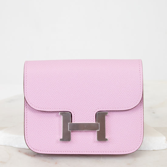 Pink wallet with a metallic 'H' logo on a light background