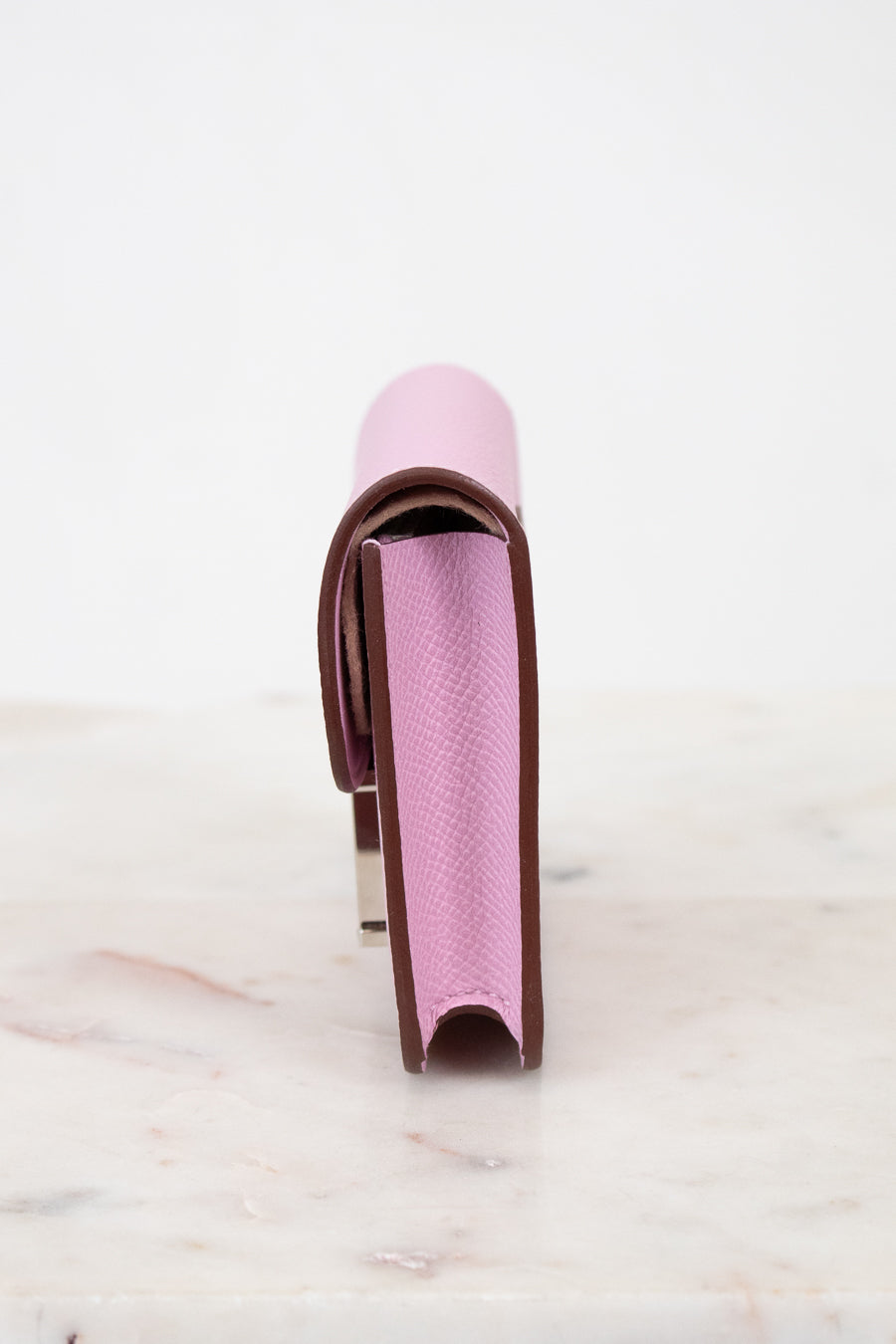 Pink and brown wallet on a marble surface