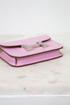 Pink handbag with a silver clasp on a light wooden surface