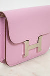 Pink handbag with a gold logo on a light background