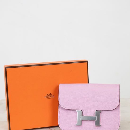 Pink handbag with silver hardware next to an orange Hermes box on a light background