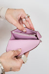 Close-up of hands holding a pink wallet with a white background