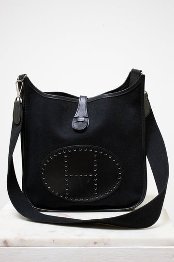 Black handbag with "H" detail on a white background