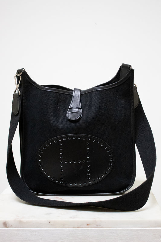 Black handbag with "H" detail on a white background