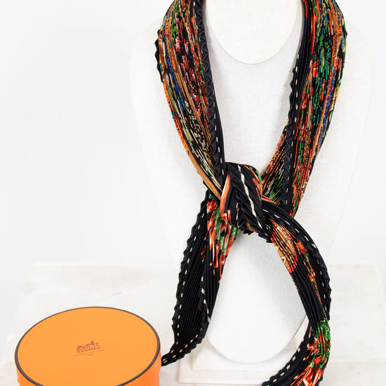 Colorful patterned scarf on a necklace best with an orange box below on a white background