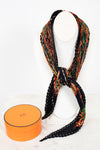 Colorful patterned scarf on a necklace best with an orange box below on a white background