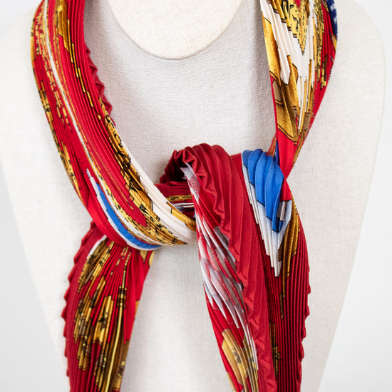 Colorful scarf with gold, blue, and red patterns on a mannequin against a white background