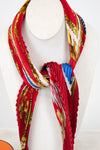 Colorful scarf with gold, blue, and red patterns on a mannequin against a white background