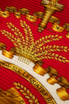Close-up of a detailed coat of arms with gold elements on a red background