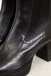 Close-up of black leather boots with a platform sole on a white background