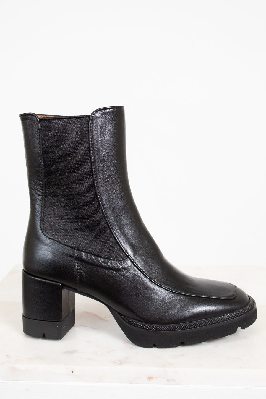 Black leather boots with a block heel on a white background