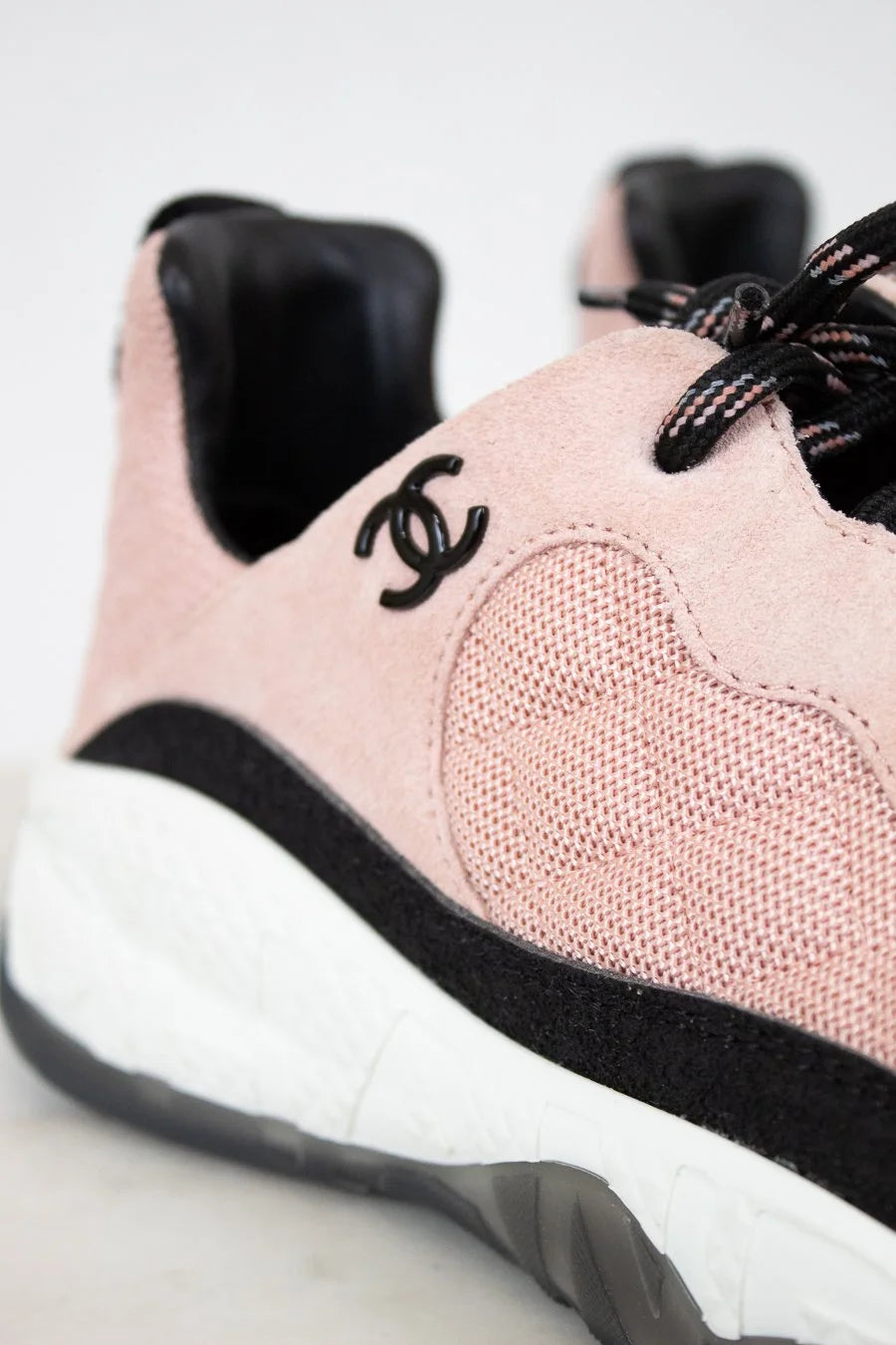 Pink sneaker with black laces and heart design on a light background