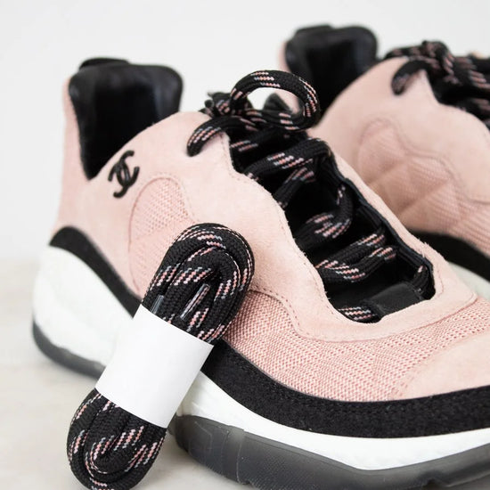 Pink sneakers with black laces and a white sole on a light background