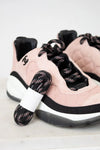 Pink sneakers with black laces and a white sole on a light background