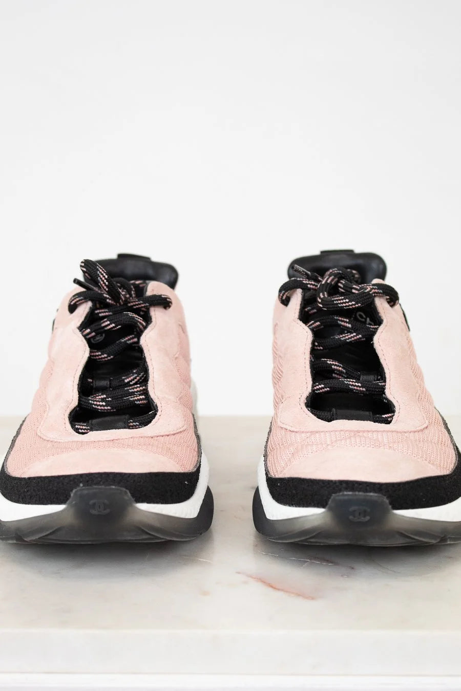 Pair of pink sneakers with black laces on a white background