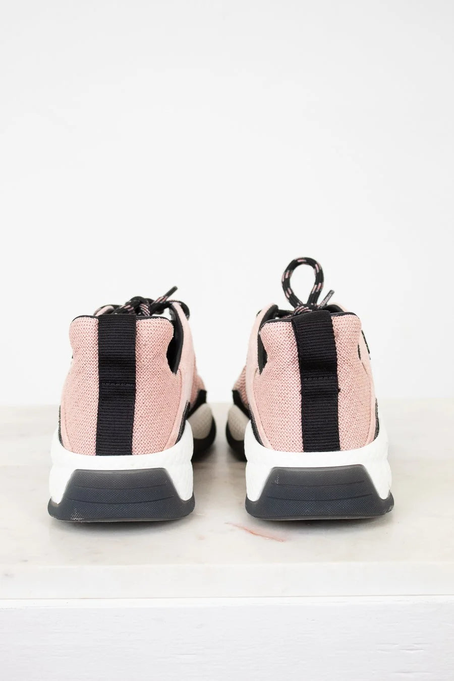 Pink sneakers with black accents on a light gray background
