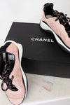 Pink and black Chanel sneakers on a Chanel box with a white background